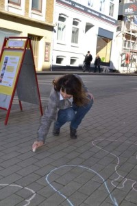 Eine Frau setzt gerade die Straßenmalkreide an.